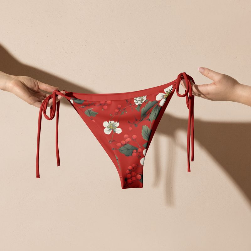 Orange-red string bikini bottoms have forest flowers and wild berries printed on them. 