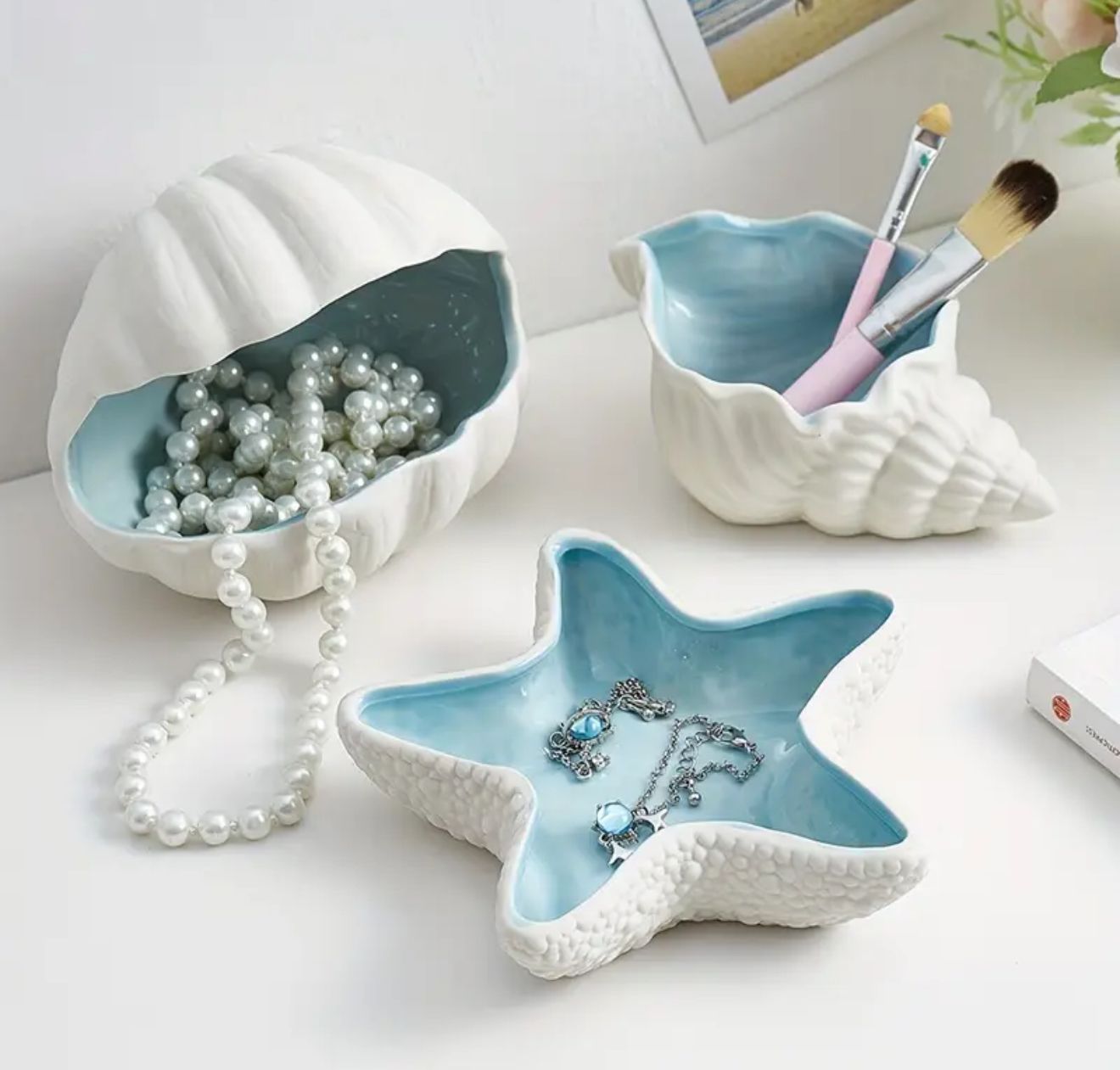 The Coastal Charm Set — Three ceramic ring dishes inspired by the ocean’s natural beauty. Featuring a conch, seashell, and starfish design, this collection combines artistry and function The Coastal Charm Set — Three ceramic ring dishes inspired by the ocean’s natural beauty. Featuring a conch, seashell, and starfish design, this collection combines artistry and function