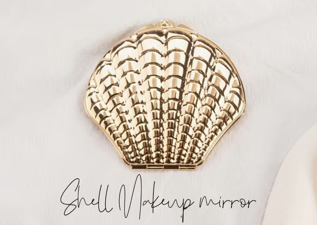 The Ocean Shell Pearl Mirror — A compact golden shell mirror with a lustrous metallic frame and polished glass interior. Designed to slip elegantly into any vanity or handbag The Ocean Shell Pearl Mirror — A compact golden shell mirror with a lustrous metallic frame and polished glass interior. Designed to slip elegantly into any vanity or handbag