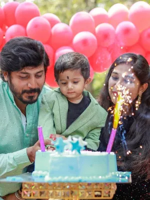 Joyful family celebrating a child&#39;s birthday with a vibrant cake, balloons, and sparkling candles, highlighting the perfect occasion for Customized Return Gifts by Human Birds International®, featuring eco-friendly seed ball packs tailored for memorable celebrations.