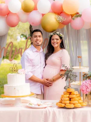 Happy couple celebrating a baby shower with a pastel-themed setup, including balloons, a cake, and decorations, showcasing a perfect occasion for Customized Return Gifts by Human Birds International®, featuring eco-friendly seed ball packs for unforgettable milestones.