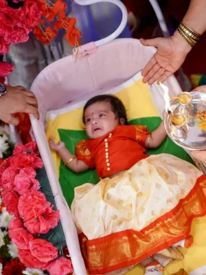 Joyful family celebrating a baby&#39;s naming ceremony with colorful decorations, cake, and traditional elements, perfect for Customized Return Gifts by Human Birds International®, featuring eco-friendly seed ball packs to commemorate special occasions.