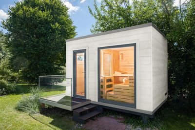 Modernes Saunahaus mit weißer Holzfassade, Flachdach und klarer Linienführung – ein stilvoller Rückzugsort für den Garten.