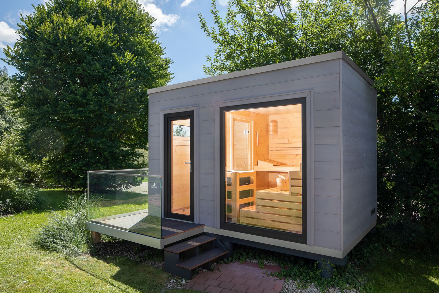 Kompaktes Saunahaus (ca. 3,75 × 2,45 m) mit massiven Blockbohlenwänden und Holzfenstern – verbindet natürliche Materialien mit zeitgemäßem Design
