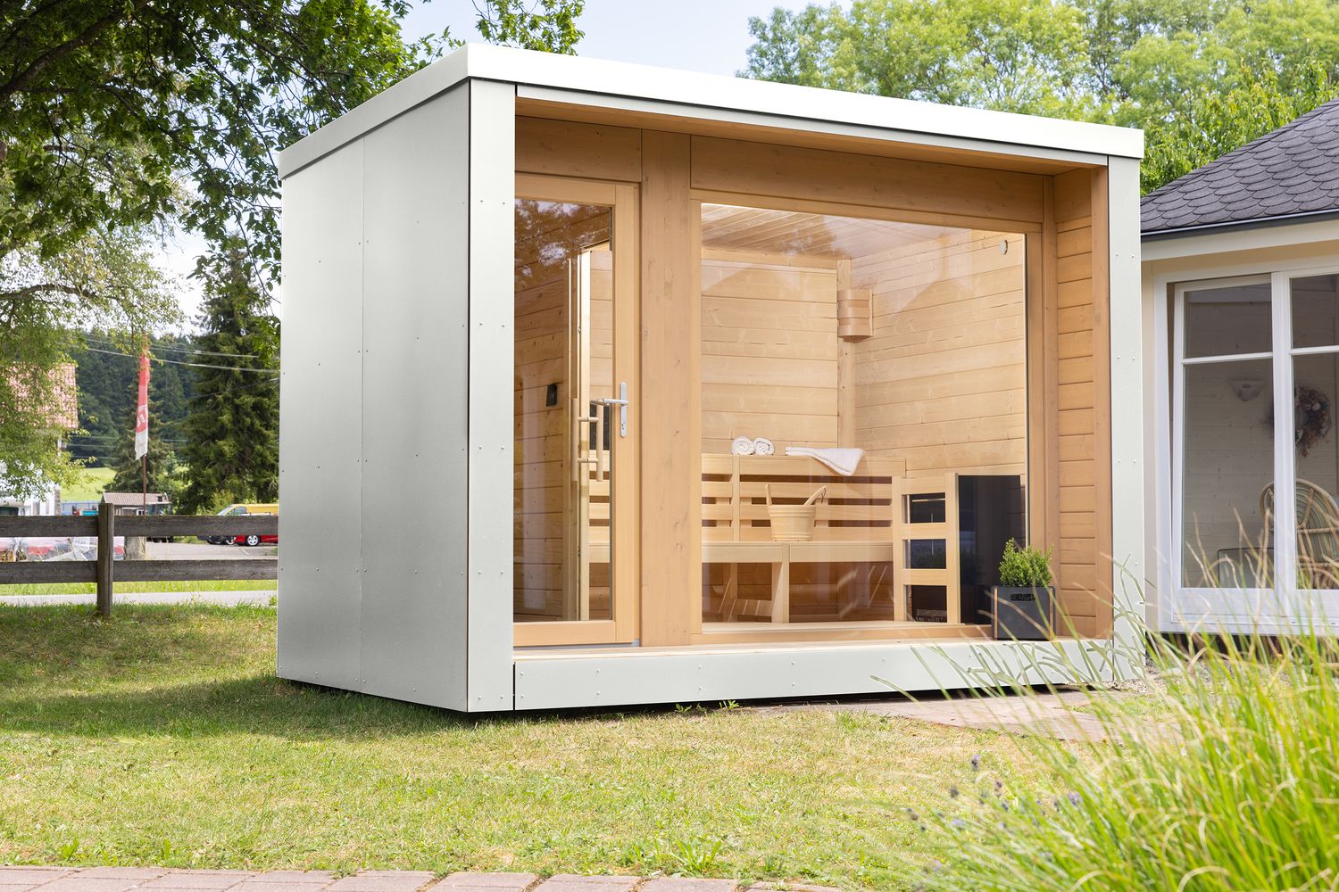 Design-Saunahaus mit klarer Kubusform, weißer HPL-Fassade und großzügigen Fensterflächen – bietet ganzjährigen Komfort im Außenbereich.