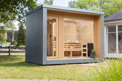 Modernes Saunahaus mit grauer HPL-Fassade, flachem Dach und klarer Linienführung – ein stilvoller Rückzugsort für den Garten.