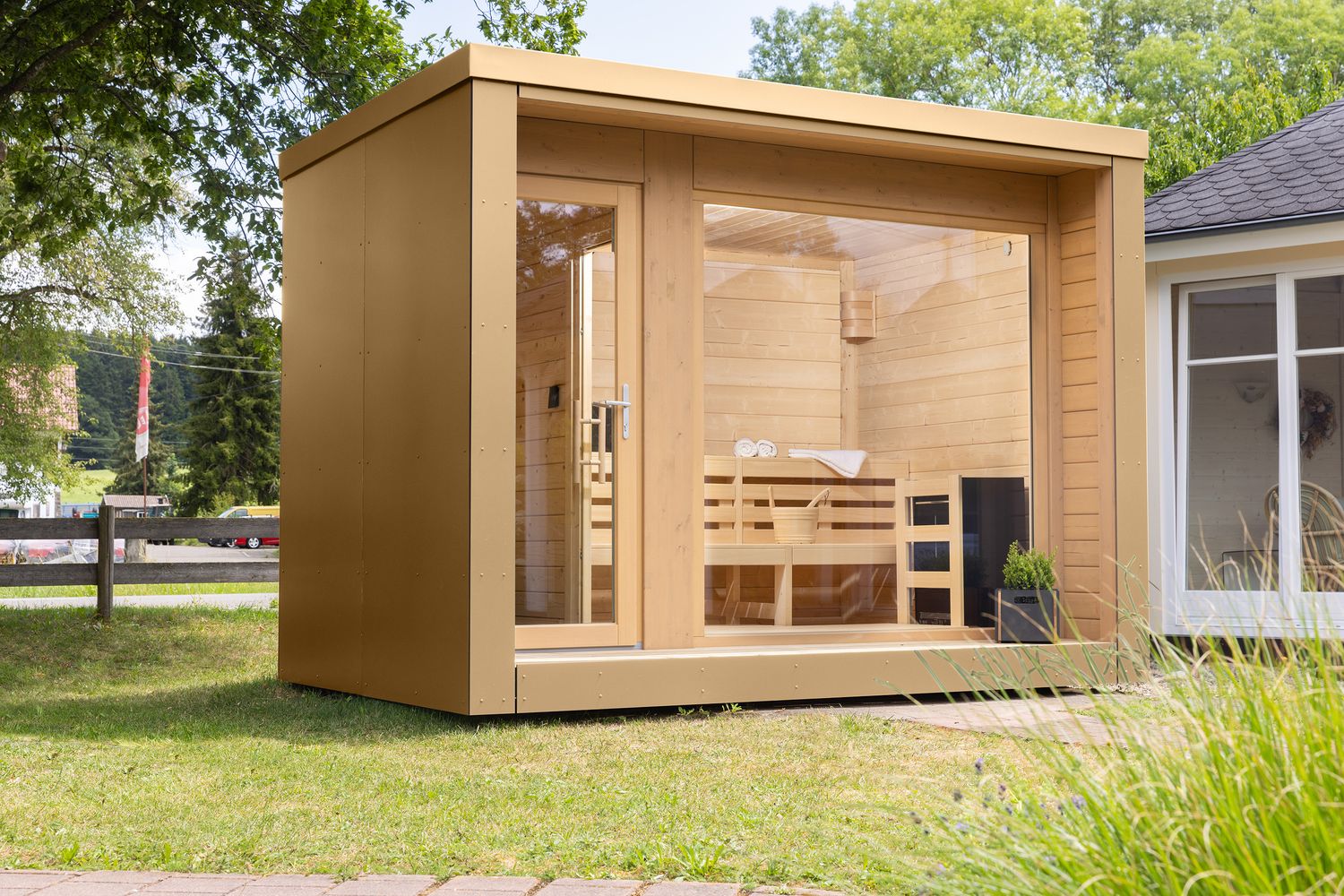 Design-Saunahaus mit hochwertiger HPL-Verkleidung in Sand- und Brauntönen, flachem Dach und großzügiger Fensterfront – ideal für moderne Gartenlandschaften.