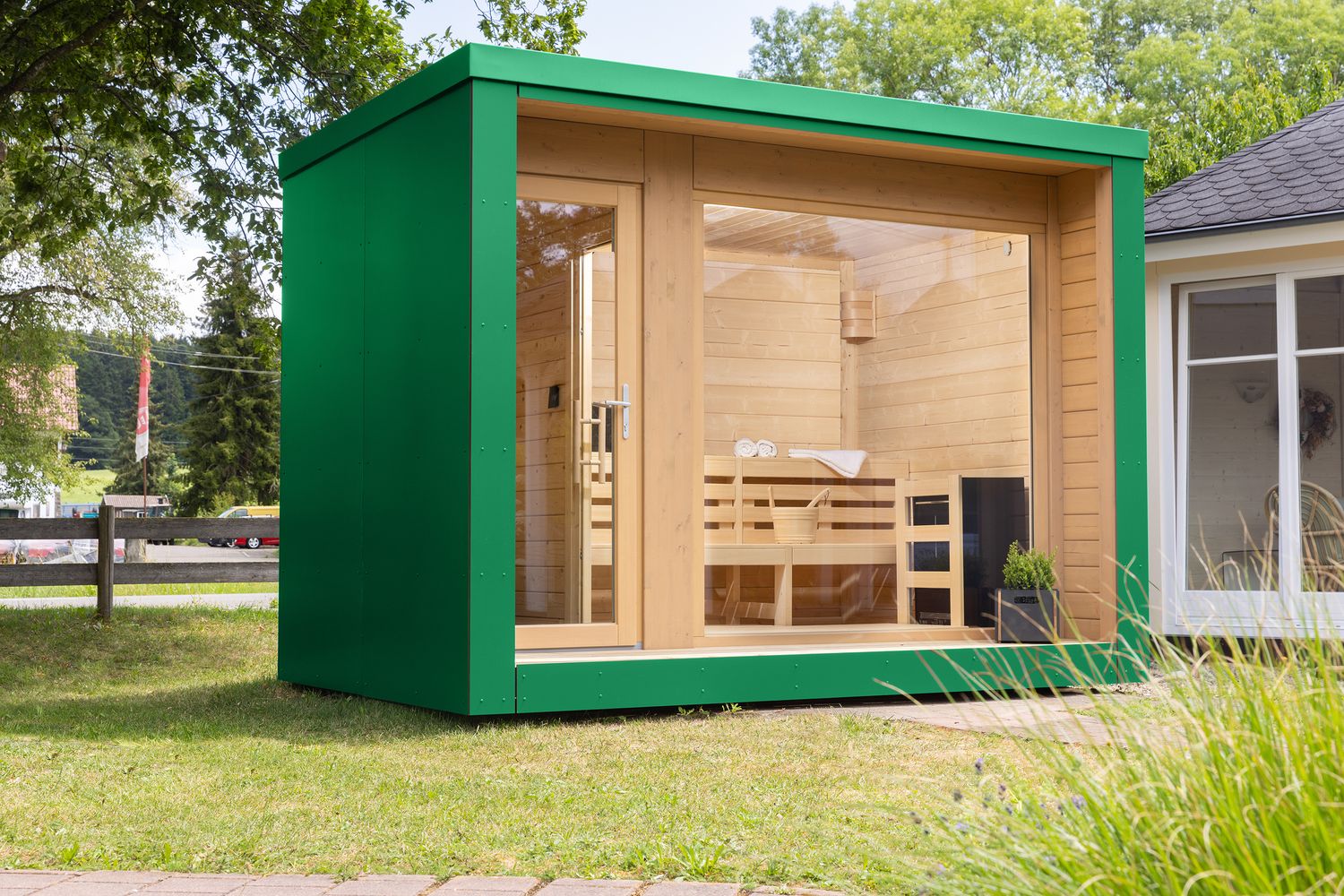 Exklusives Gartensauna-Modell mit großzügiger Glasfront und grünen Fassadenplatten – verbindet modernes Design mit natürlicher Umgebung.​

