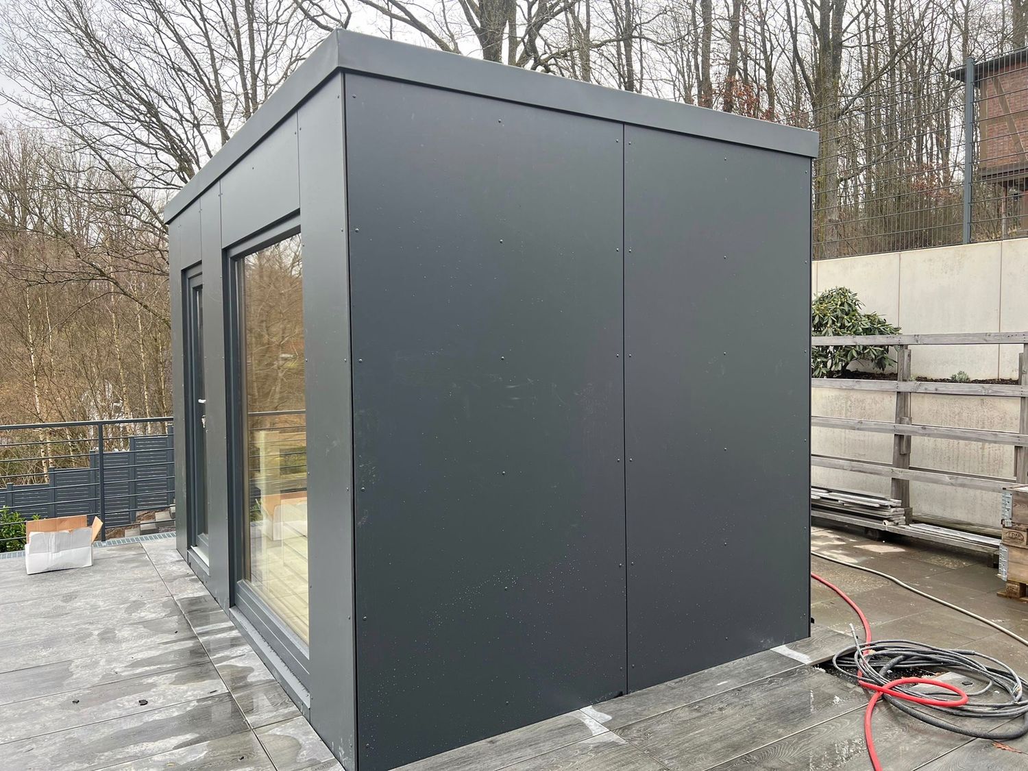 Seitenansicht der exklusiven Outdoor-SaunaBloox mit anthrazitfarbener HPL-Verkleidung und Flachdach