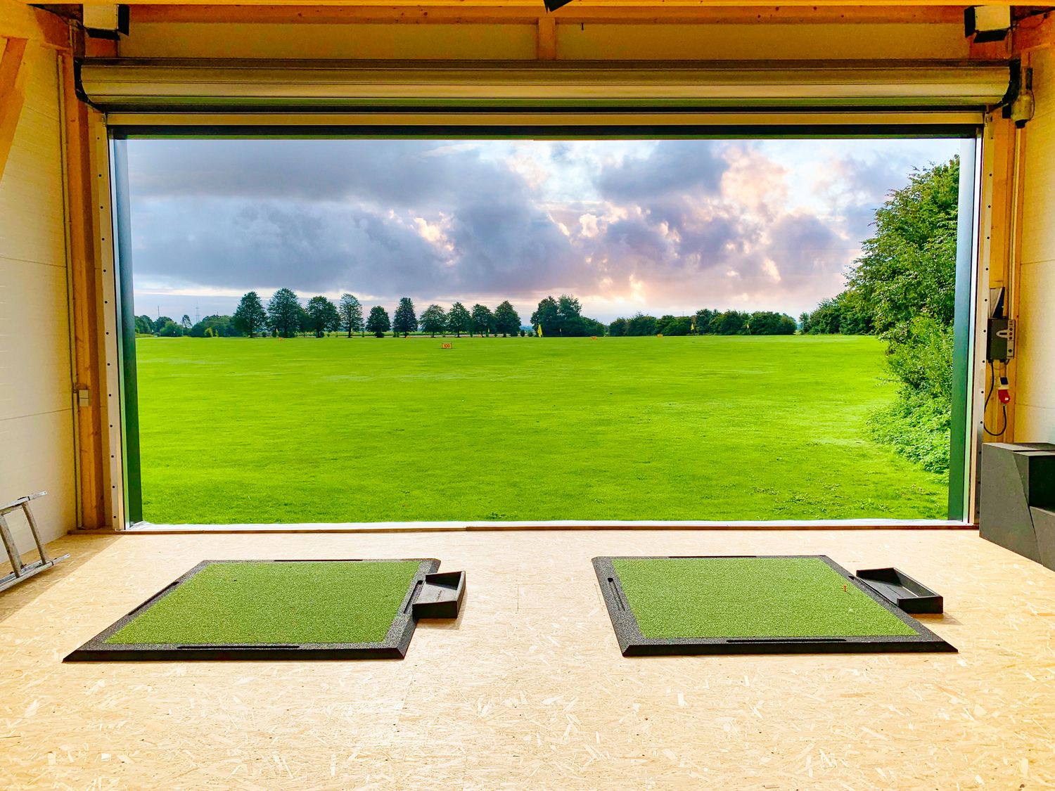 Blick aus der Indoor-Golfhalle auf die Driving Range – ideale Bedingungen für Ganzjahrestraining