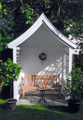 Philosophenbank an einer Hauswand mit Blumentöpfen – dekorativer Ruheplatz im Außenbereich