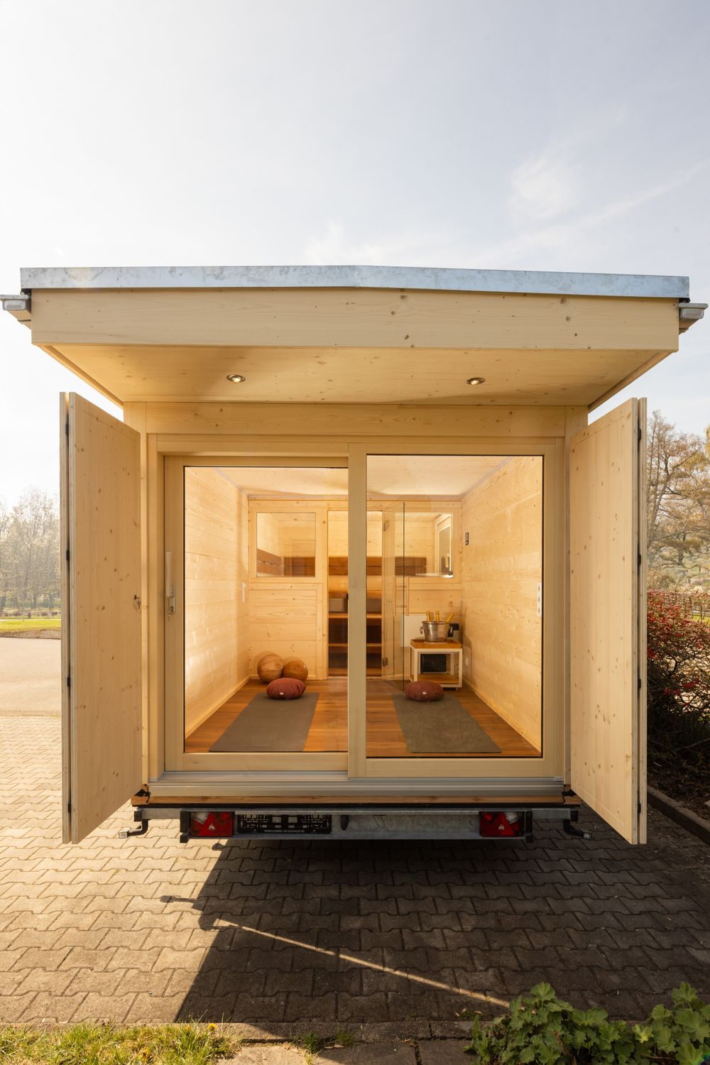 Blick durch Schiebetür in mobile Sauna – moderner Innenraum aus Holz mit hochwertiger Saunaausstattung