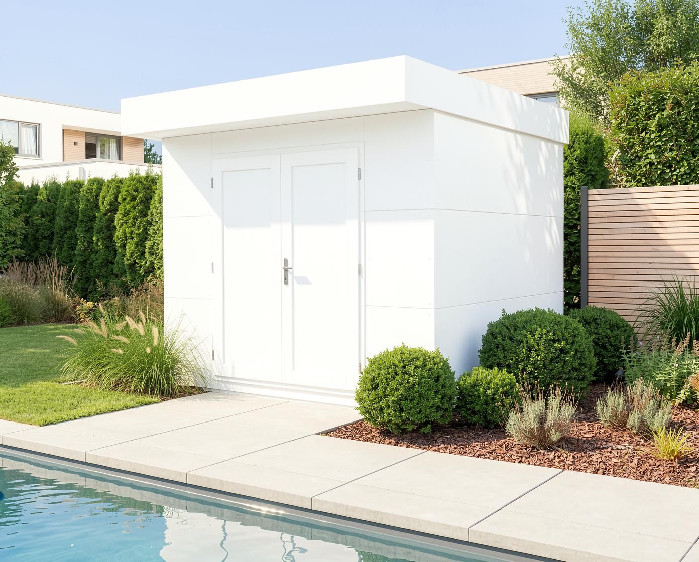 Exklusives GeräteBLOOX Cube White Edition mit weißer HPL-Fassade als modernes Pooltechnikhaus in hochwertiger Designer-Garten