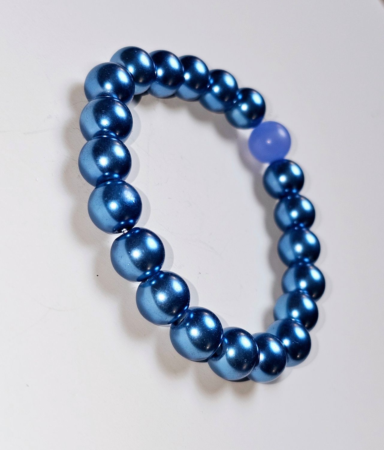 a sleek design with metallic blue beads and a single, light purple accent bead, this bracelet exudes a subtle yet captivating charm. I