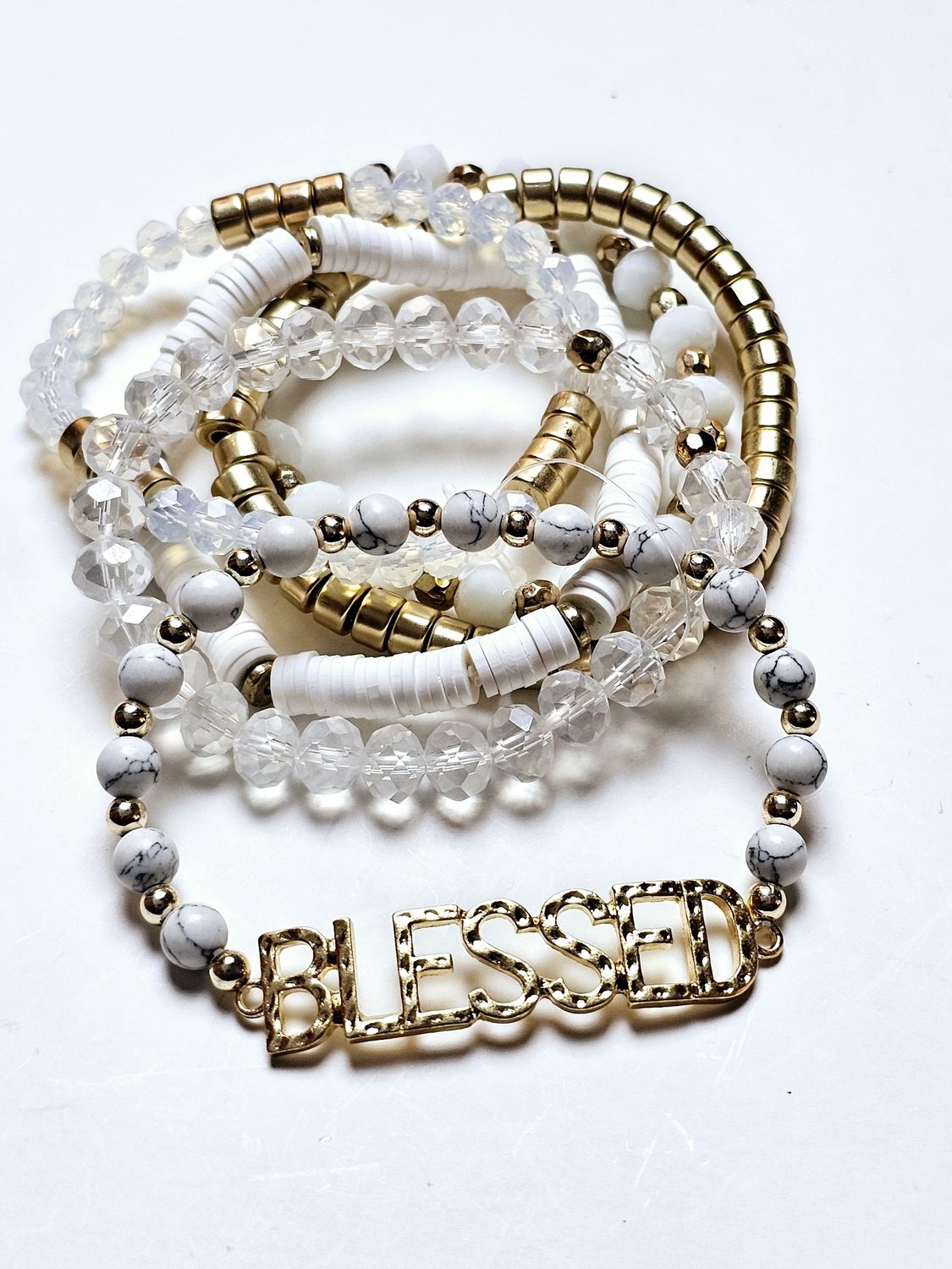 Radiant Harmony Bracelet Set, a stunning collection of bracelets featuring marbled white beads, clear faceted accents, and sleek gold details. The highlight of the set is a bold, gold-toned &quot;BLESSED&quot; charm, serving as both a fashionable statement and a reminder of gratitude and positivity. Perfect for stacking or wearing individually, these bracelets are versatile accessories that bring a touch of elegance and inspiration to any outfit.