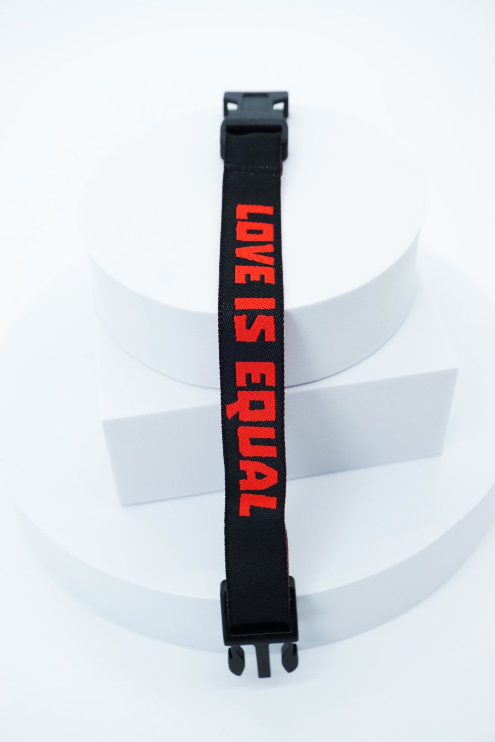 Pride Armband mit Schriftzug Love is Equal in den Farben rot auf schwarz gewebt. Robuster Klippverschluss. Handgenaeht in Deutschland. Ansicht in geschlossenen Zustand.