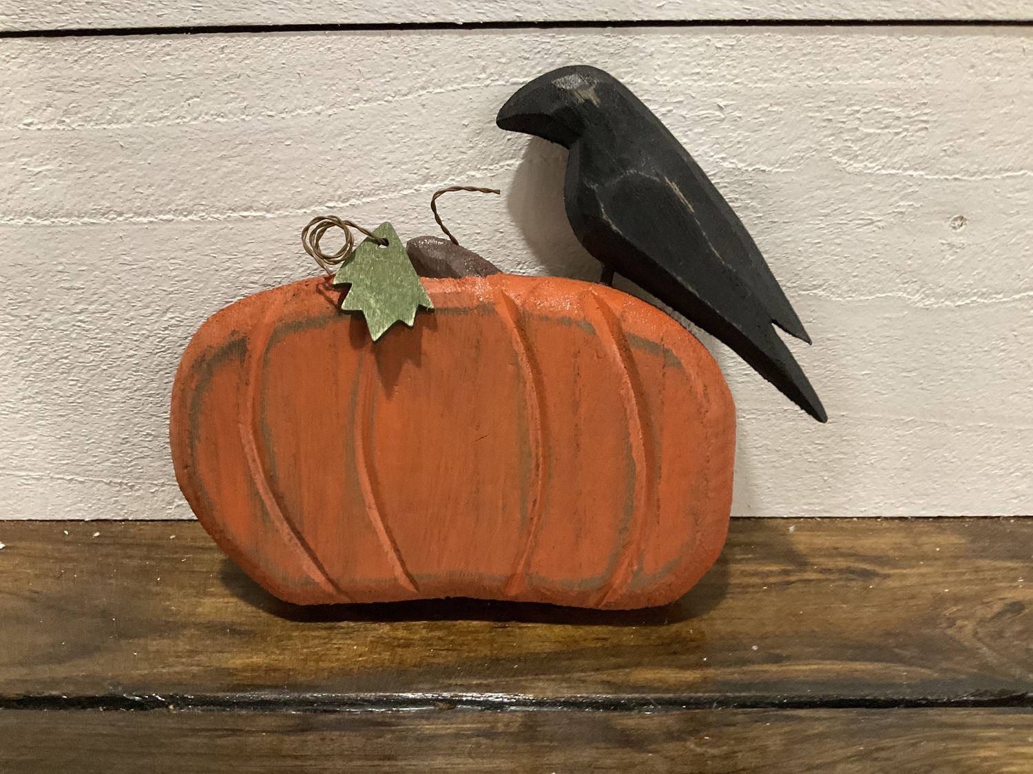 Distressed carved wooden crow on pumpkin
