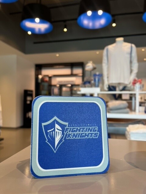 Royal blue coaster with light blue outlining it and white Lynn logo on the front and text saying &quot;Fighting Knights.&quot;