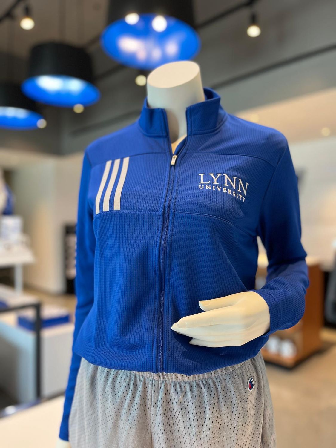 choice between royal blue and gray full-zip jacket with three stripes on the right side of the chest and text on the left side saying &quot;Lynn University.&quot;