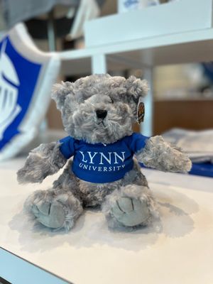 gray teddy bear wearing a royal blue t-shirt with white lettering saying &quot;Lynn University.&quot;