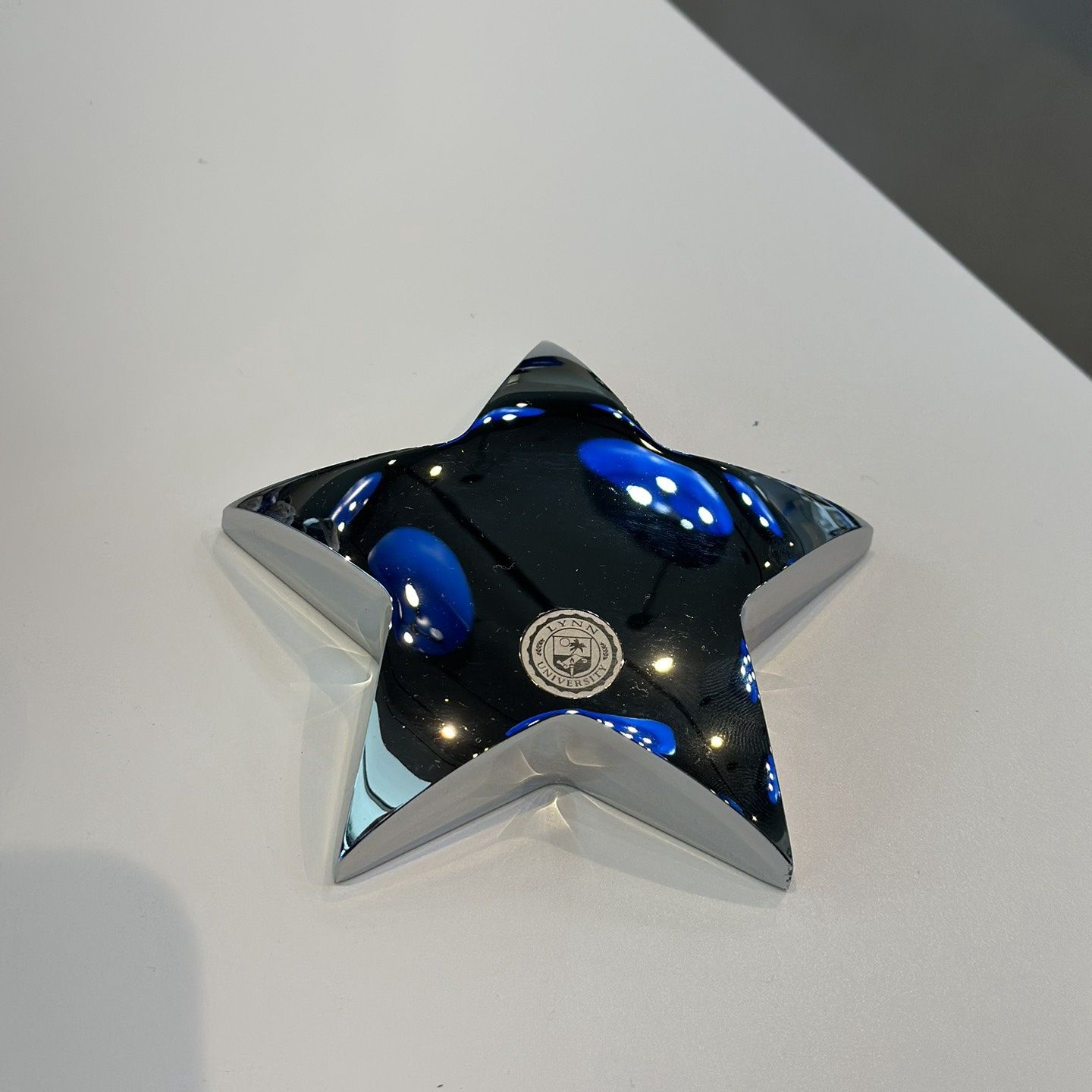 silver star paperweight with logo on the front.