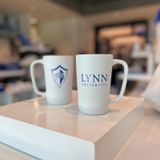 White mug with blue text on the front saying &quot;Lynn University&quot; and blue/white spirit logo on the back.