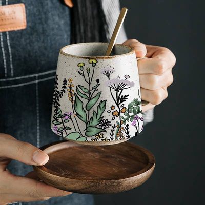 The Artsy Em&#39;s Floral Harmony Stoneware Mug is a beautifully crafted, artisanal mug that combines elegance and charm. Made from durable stoneware, it features a hand-painted floral design, giving each mug a unique, one-of-a-kind look. The earthy tones and intricate patterns evoke a sense of warmth and nature, making it perfect for enjoying coffee, tea, or any hot beverage. 