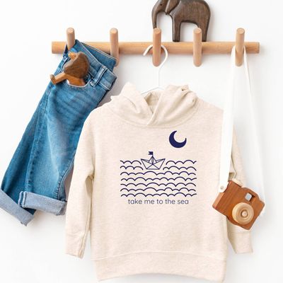 The Take Me to the Sea Ocean Kids Hoodie by Spruce Seed is a cozy and stylish fleece pullover designed for kids. Featuring a beach coastal theme, this unisex hoodie is perfect for young adventurers who love the ocean. Made for all seasons, it’s ideal for cooler weather or a windy day at the beach. 