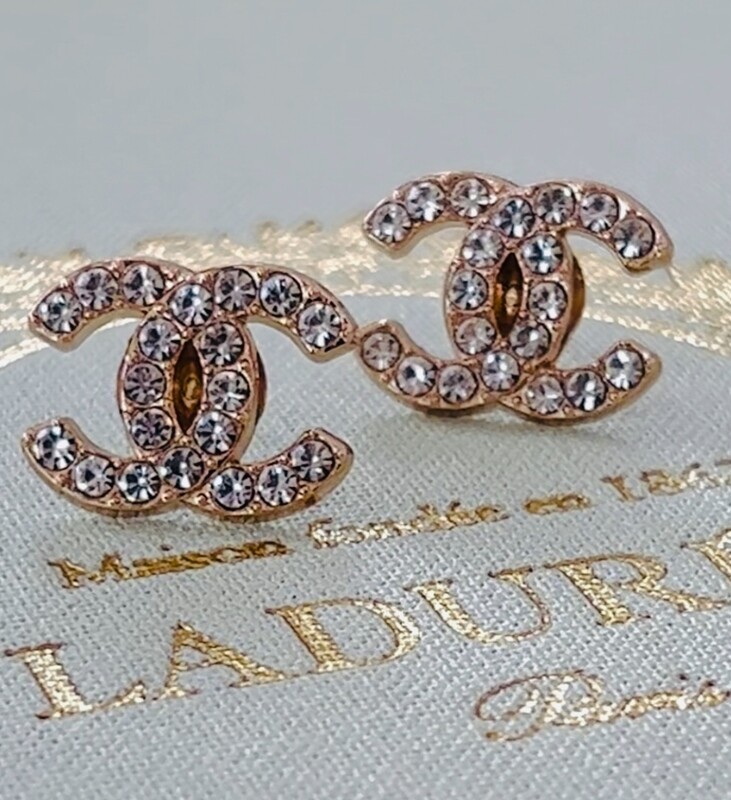 Delicate gold earrings with small rhinestones logo