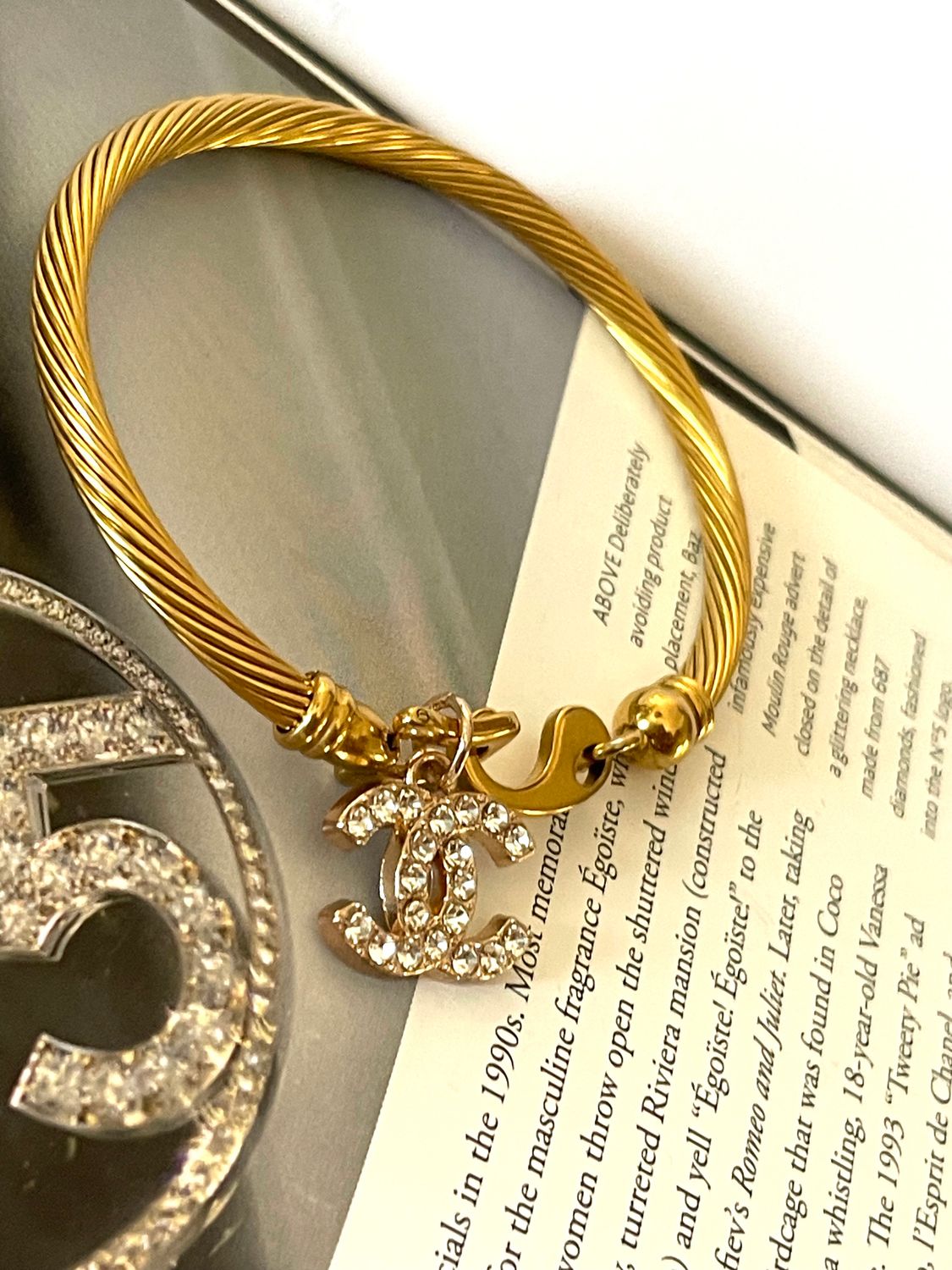 Delicate bracelet with small charm logo with rhinestones