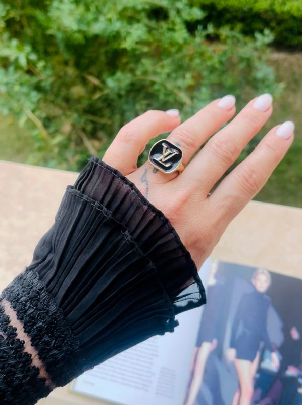 Elegant gold tone ring with black logo button