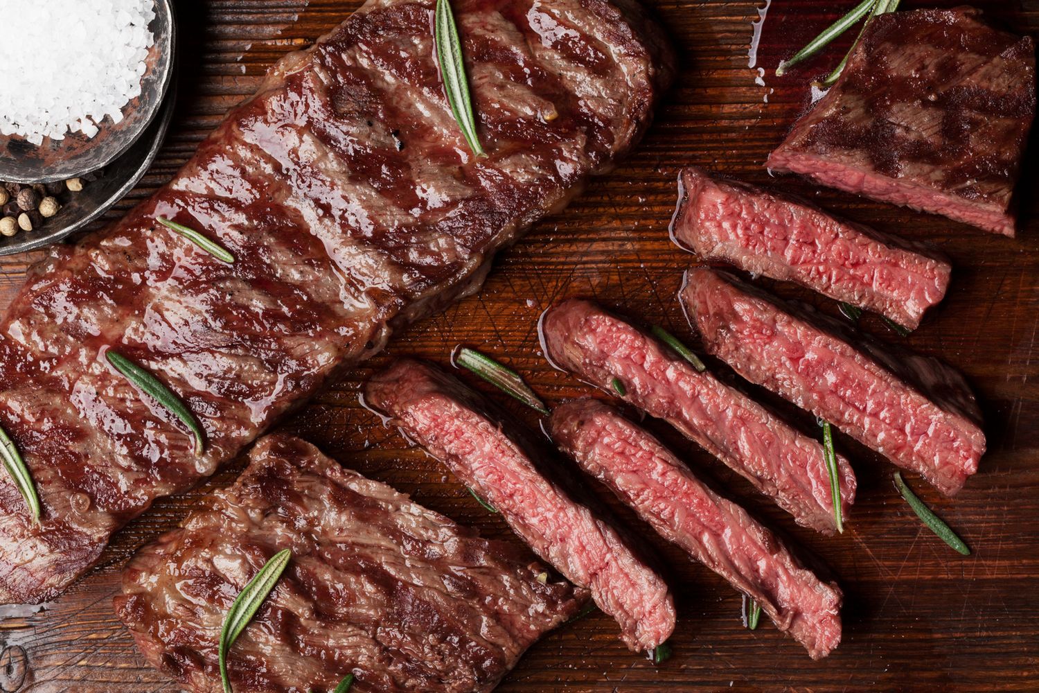 Flatiron Steak Perfectly grilled Grass-Fed Flatiron Steak from Tennessee, garnished with rosemary and sea salt on a rustic wooden board.