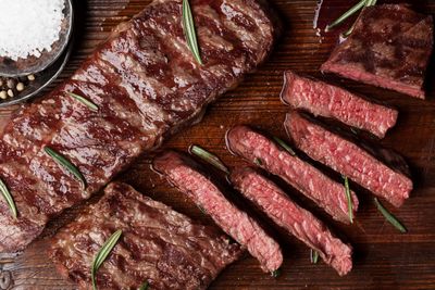 Perfectly grilled Grass-Fed Flatiron Steak from Tennessee, garnished with rosemary and sea salt on a rustic wooden board.