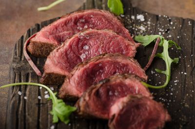 Sliced Grass-Fed Beef Tenderloin from Tennessee, cooked medium-rare and sprinkled with sea salt on a rustic board.