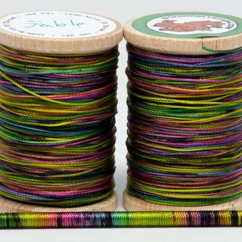Two spools of Fable thread with a thin rod wrapped in thread showing the colors.