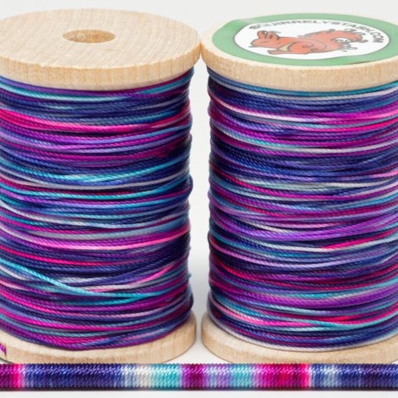 Two spools of Jazz thread with a thin rod wrapped in thread to display colors.