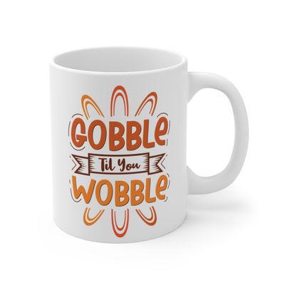 11 oz ceramic coffee mug with Gobble Til You Wobble playful Thanksgiving text and graphic on both sides. Mug features a C-handle and rounded corners, perfect for enjoying hot beverages like coffee, tea, and hot chocolate.