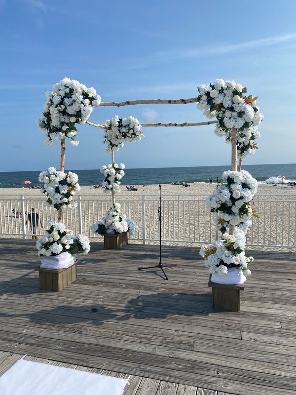 A stunning white floral wedding chuppah at cape may convention center in cape may new jersey featuring hydrangeas and roses