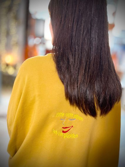 Sweater mit Stickerei Pullover in senfgelb mit einer Stickerei, Bitte nicht stören. Ich bin glücklich. Mit einem lachenden Gesicht dazwischen.