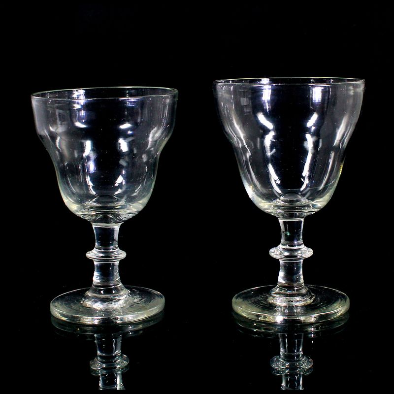 2 stemmed glasses made of colorless glass with a ball base and a pressed knop, first half of the 19th century.