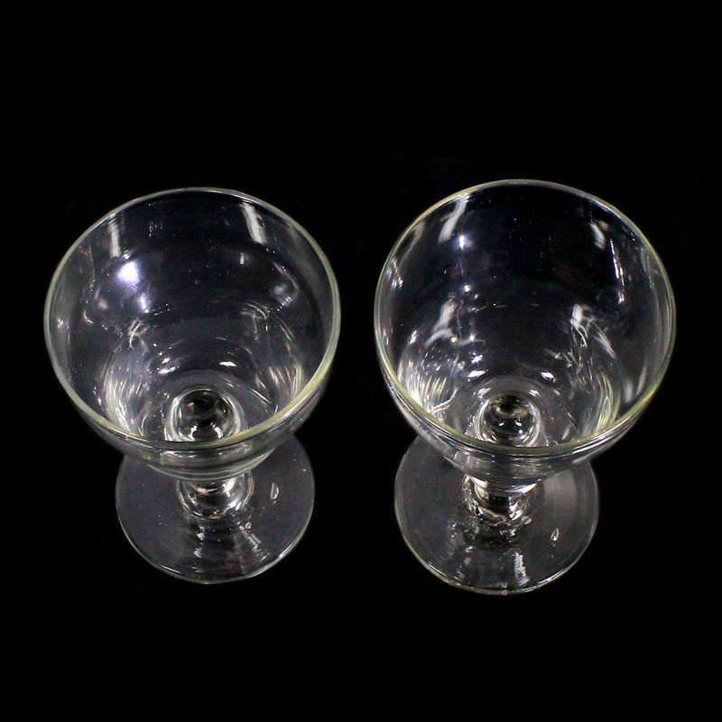 2 stemmed glasses made of colorless glass with a ball base and a pressed knop, first half of the 19th century.