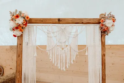 Makramee-Traubogen mit Blumen dekoriert bei einer Boho-Hochzeit in der Schweiz – perfekte Deko für freie Trauungen