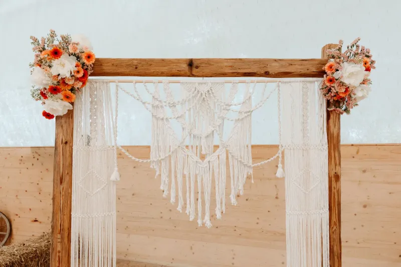 Makramee-Traubogen mit Blumen dekoriert bei einer Boho-Hochzeit in der Schweiz – perfekte Deko für freie Trauungen