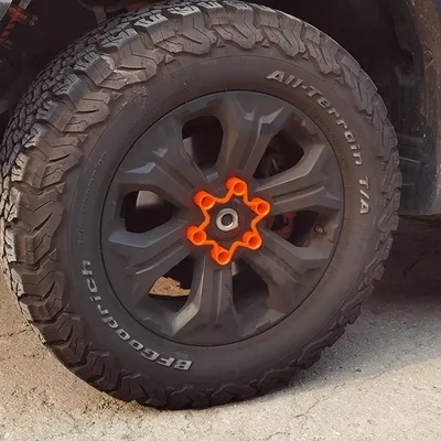 A 6-stud wheel with a fluoro orange long-barrelled wheel nut locker installed