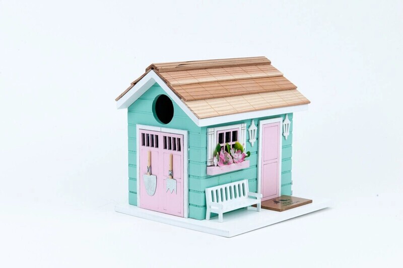 Front view of a mint green She Shed birdhouse with pink door and white picket fence detail.