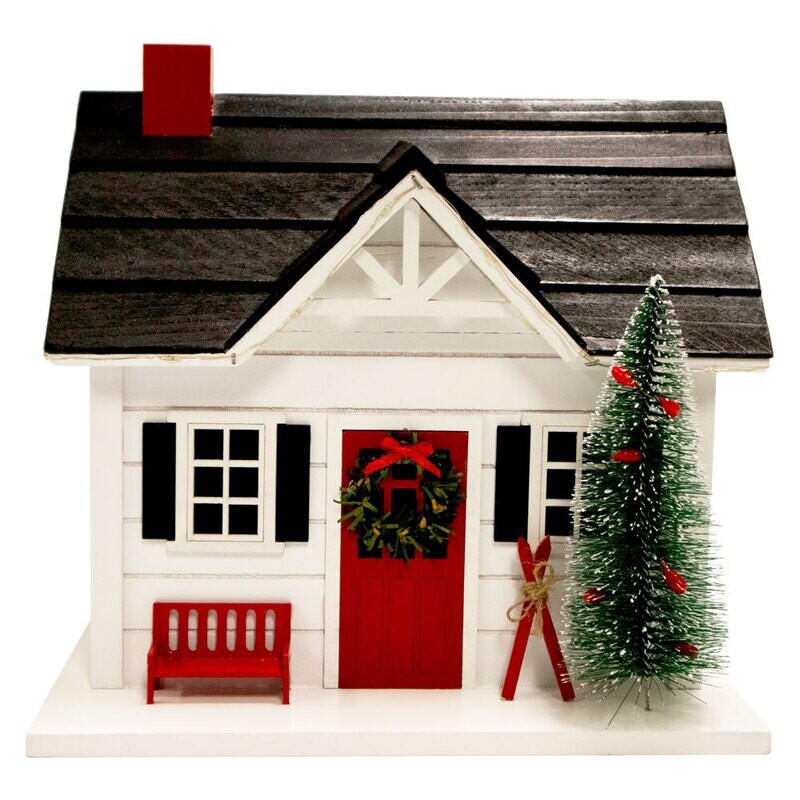 Front view of a white ski chalet birdhouse with a red door, green wreath, and miniature skis.