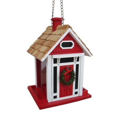 Side angle of the Christmas cottage feeder showing the red wood siding, white window trim, and sturdy hanging chain.