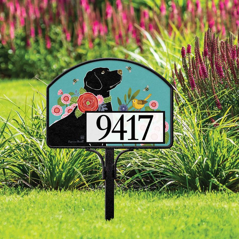 Magnetic yard sign featuring a black dog, pink flowers, and address numbers, installed in a garden.