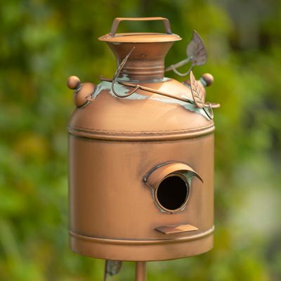Antique copper milk can birdhouse with decorative vine and leaf metalwork accents.