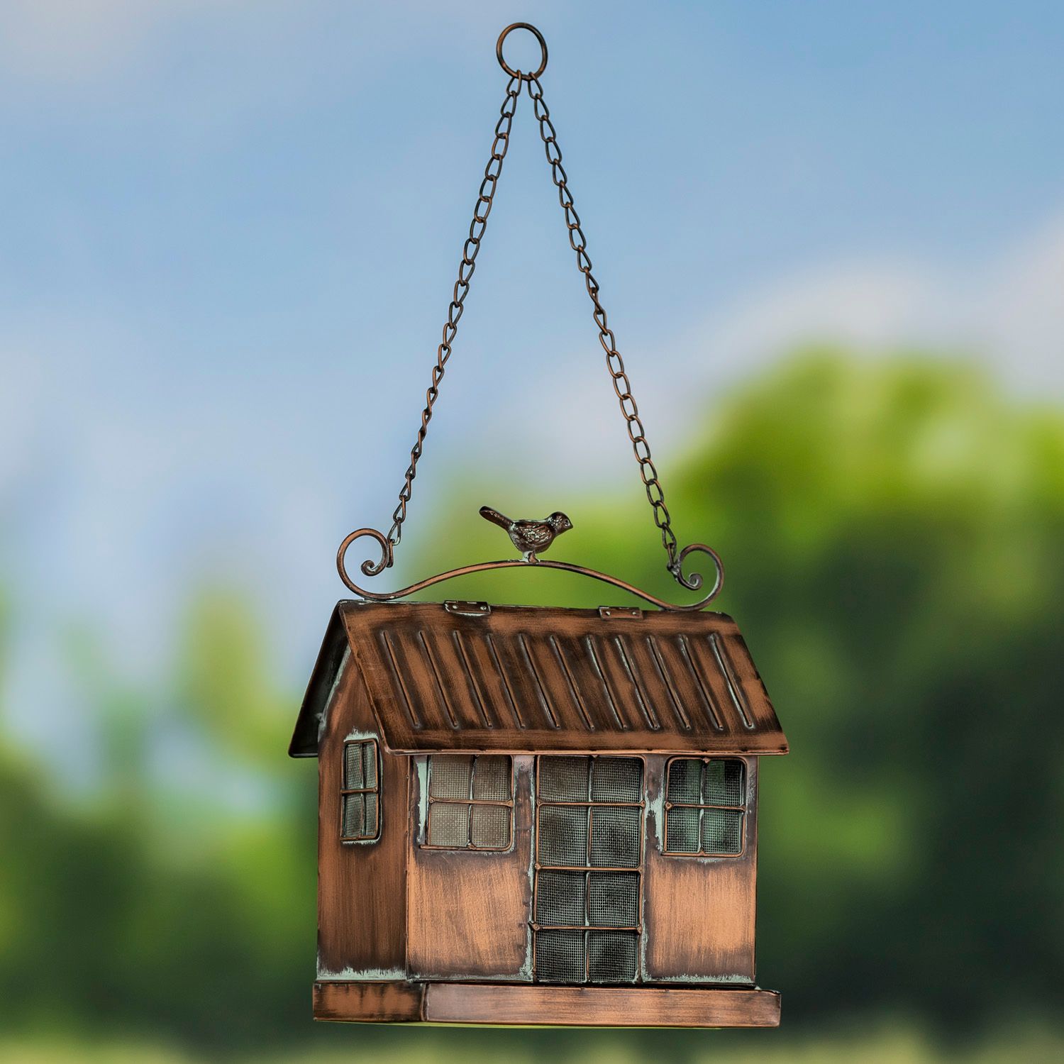 Hanging cottage-style bird feeder with antique copper finish, mesh seed center, and bird ornament.